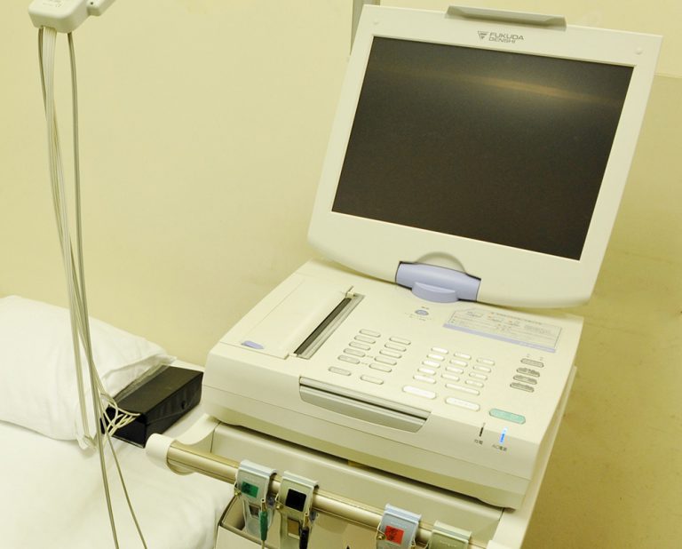 医務室の心電図検査機器。白い大型医療機器が設置されている。